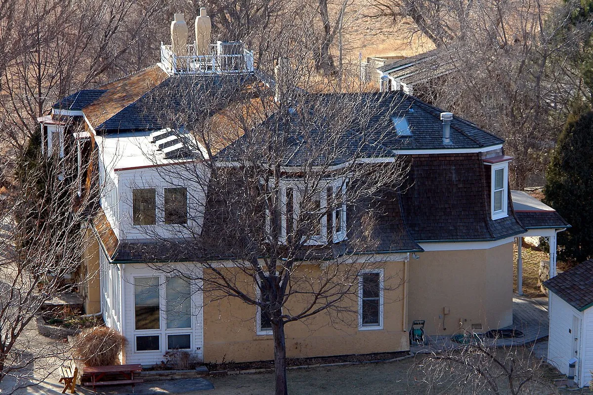 The historic Sandstone Ranch house, now the park's visitor center, a two-storey farmhouse with a mansard roof and white dormers, seen from above through bare trees on a February afternoon.